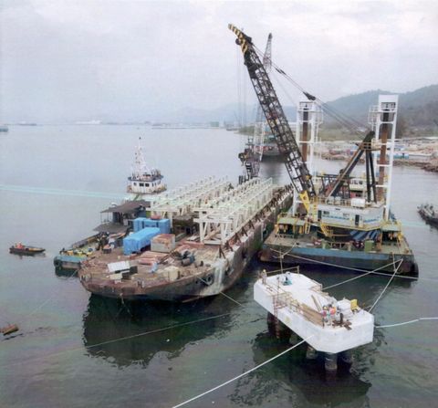 Crane barge di samping deck barge bermuatan struktur baja jetty, dekat tiang jetty